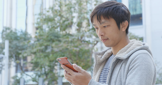 Asian Man use of mobile phone in city