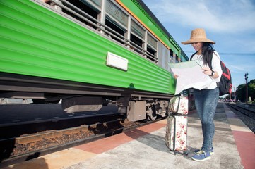 Fototapeta na wymiar Pretty Asian traveler backpacker female looking map and waiting train at railway station in Thailand.