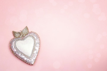 Decorative heart with wings on pink background. Space for text.