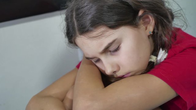 girl kid child sadness loneliness standing near the wall hugs knees on the bed embraces indoors herself depression