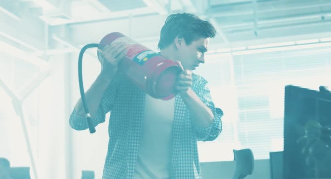 Employees working in smoky office. Angry guy bringing extinguisher and trying to break computer. Smoke clearing, guy looking surprised.