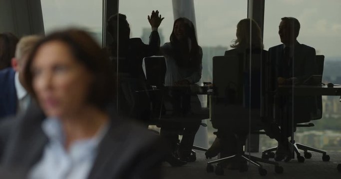 4k, Group of businesspeople high five together while standing in a modern boardroom. Slow motion.