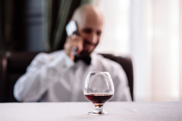 A glass of cognac on a background of men.