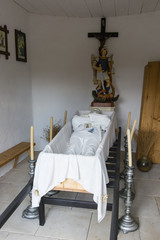 A figurine of a mortal in an open coffin in a village morgue.