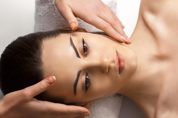 Obraz na płótnie Canvas Pretty young girl with thick eyebrows and perfect skin doing facial massage, beauty photo concept, hands on face, skin care, closed eyes, close up.