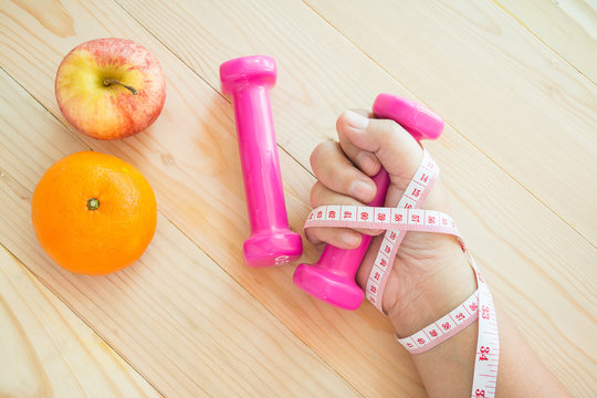 hand holding dumbell with Tape measure and fruite.Diet and exercise