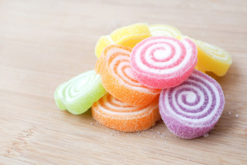 Bulk of colorful gummy jelly candy rolls with sugar, Put on wooden tray.