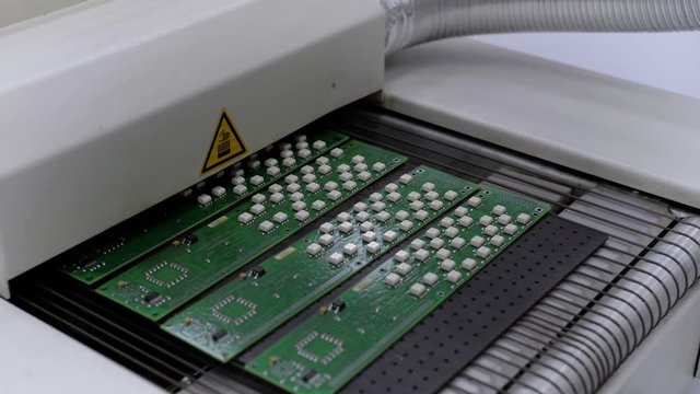 Electronic printed circuit board leaves from air convection reflow oven.