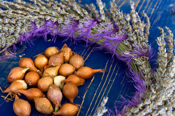 Brown onion in a peel on a blue wooden board with a lavender wreath