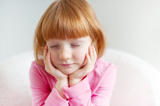 A girl with a kary hairstyle sits with her eyes closed