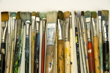 Well used artists paintbrushes on a white paper background