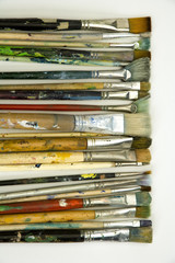 Well used artists paintbrushes on a white paper background