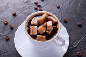 Sugar addict. Heap overabundance of sugar in a cup of coffee on a black table with scattered coffee beans