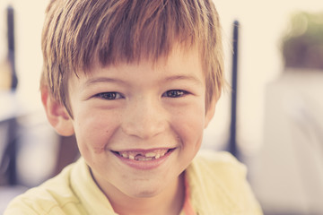 close up headshot portrait of young little 7 or 8 years old boy with sweet funny teeth smiling happy and cheerful in joy face expression