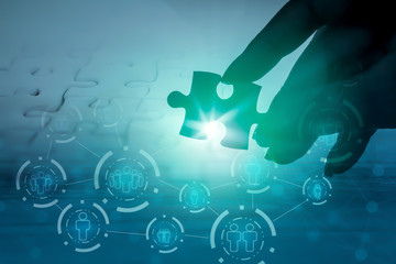 hand holding jigsaw piece with background of teamwork people connection 