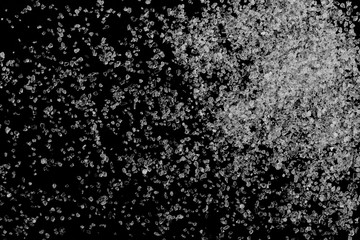 Salt grains, crystals isolated on black background, top view