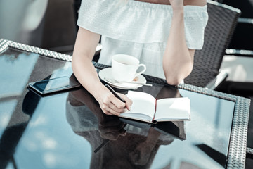 Taking notes. Close up of a notebook being on the table while being used for taking notes by a nice young woman