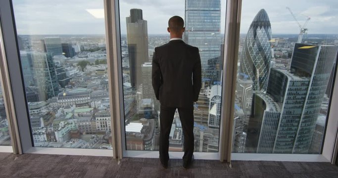 4K View from behind of African American businessman looking out at the view from London city office.