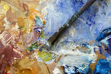 Vibrant colourful artists oil paint palette and well used brush