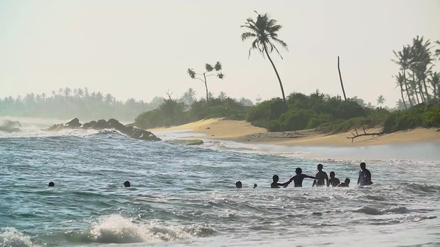 Unknown teen boys swim in the stormy ocean waves