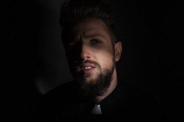 Fototapeta premium The priest is a large face in the twilight looking at the camera on a gray background