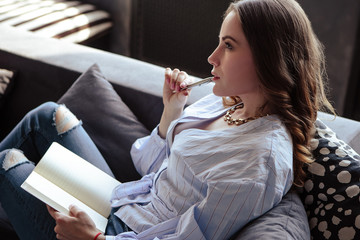 Beautiful young woman with schedule notebook in stylish home interior. Freelancer business lady in...