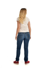 Obraz premium full length portrait of blonde lady wearing simple white shirt and jeans, standing pose isolated on white studio background.