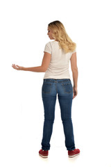 full length portrait of blonde lady wearing simple white shirt and jeans, standing pose isolated on white studio background.