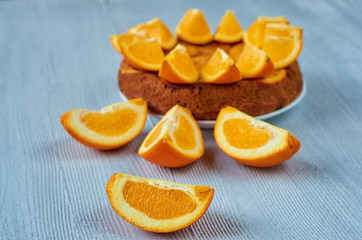 Fototapeta na wymiar Fresh orange slice on the gray table close up. Sweet caramelized orange pie with fresh fruits on the blurred background. Citrus pie. Side view