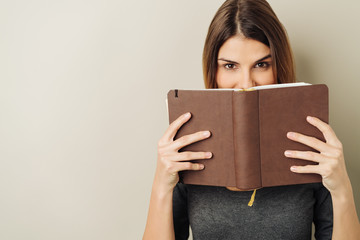 Fun young woman peering over a book