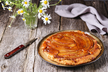 Traditional homemade banana caramel pie on vintage wooden table decorated a bouquet of chamomiles. Upside down banana cake. Selective focus 