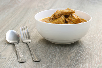 Thai Red curry with pork ribs in white bowl on Galangal leaf and wooden background. , Thai Southern style.