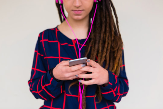 Urban Young Woman with Dreadlocks Listen to Music with a Mobile Phone