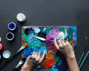 View from above, the artist's hands, the creator of the paint palette brush, different colors. The artist's tools for real art and inspiration.