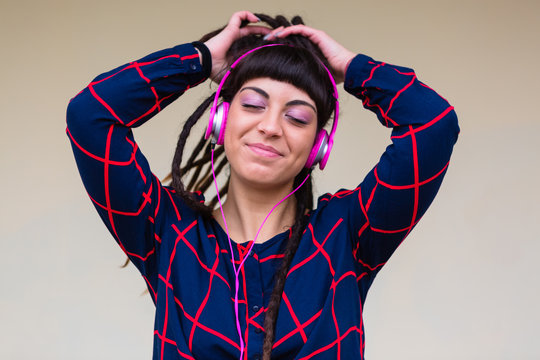Urban Young Woman with Dreadlocks Listen to Music with Pink Headphones