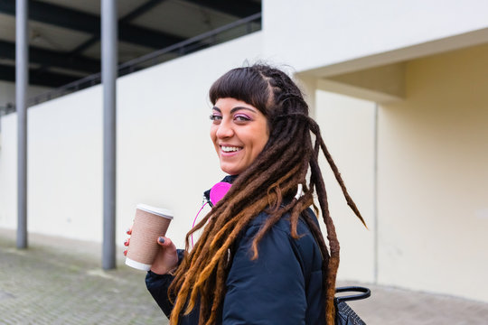 Urban Young Woman with Dreadlocks holding a Cup of Coffee Outdoors