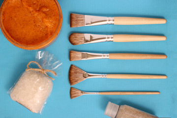 cosmetology brush with scrub abd sea salt on blue backround fashion and beauty