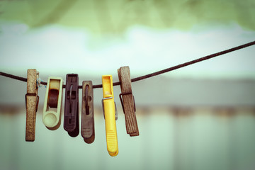 old clothespins on a rope hanging outside house, toned green, vintage look
