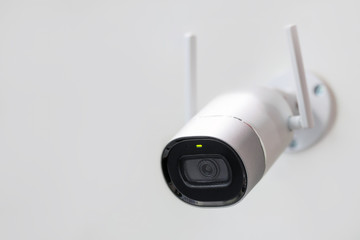 White surveillance camera. CCTV mounted on wall. Wifi wireless antennas enabled. Big brother...