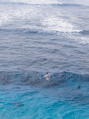 A man swim in the blue water ocean.