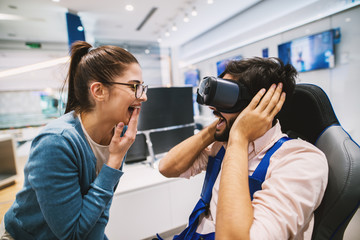Hipster young modern couple checking out VR goggles in the tech store.