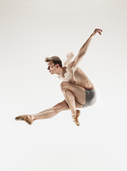 The male athletic ballet dancer performing dance isolated on white background.