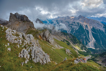 Fototapeta premium Rocks on a mountain grassy slope under dramatic clouds