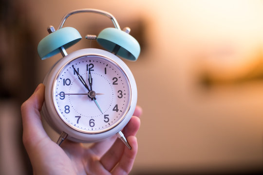 Wecker am Morgen, Sonnenlicht, gehalten in Hand