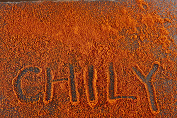 Top view on the texture background of red chilli pepper powder with text isolated on dark background