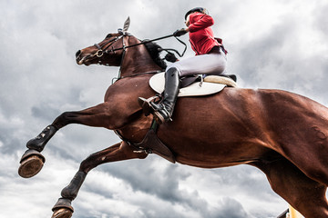 A horse with a rider jumps over an obstacle