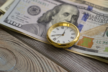 United States paper money on the table next to clock. USA dollars. Money concept. Closeup