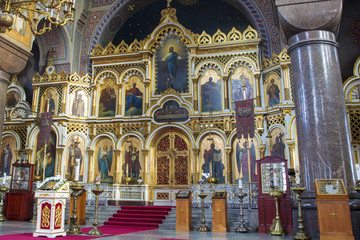 Detail of an orthodox Christian church in Helsinki in Finland. Behind the altar the classic icons of saints in a golden context. The cathedral is empty and illuminated by the sun.