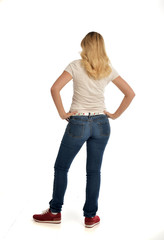 Obraz premium full length portrait of blonde girl wearing simple white shirt and jeans, standing pose, isolated on white studio background.