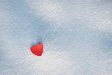 Small red heart and fresh untouched snow background